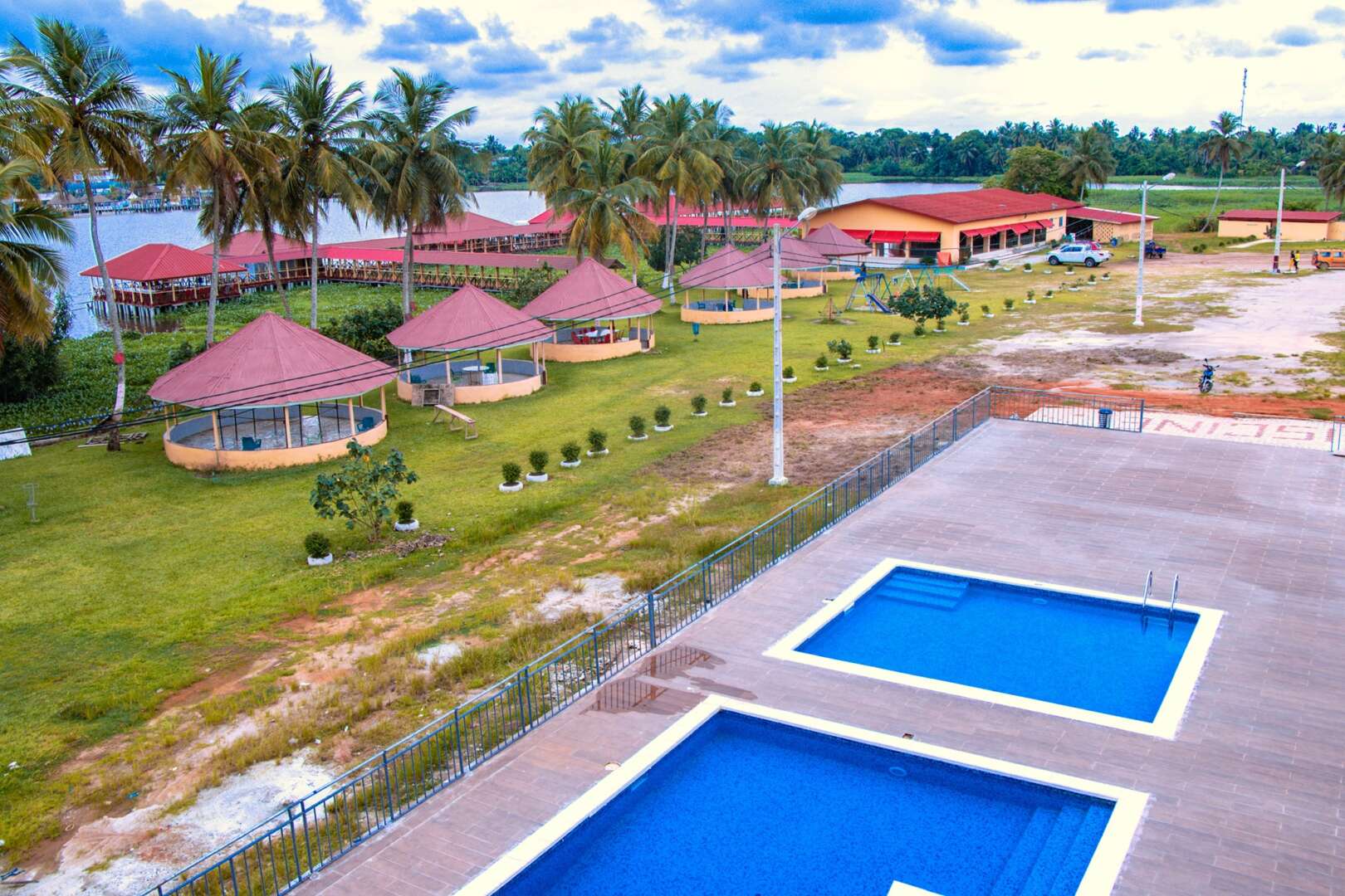 Les piscines du complexe O'bord, les paillotes et la lagune Ébrié bordée de cocotiers